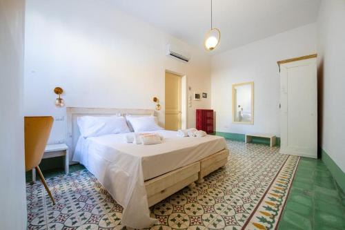 Camera matrimoniale con pavimento a cementine verdi e bianche, boiserie verde salvia e letto in legno chiaro
