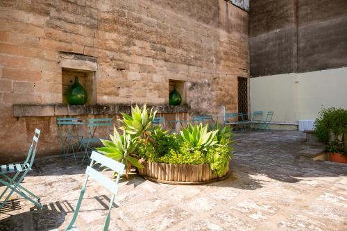 La corte interna in pietra leccese con tavolini e sedie turchesi e un'aiuola di agavi al centro